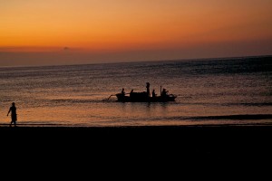 Een vissersbootje op de Bali zee bij het ondergaan van de zon.